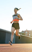 Smiling woman running outdoors in running shorts at sunset